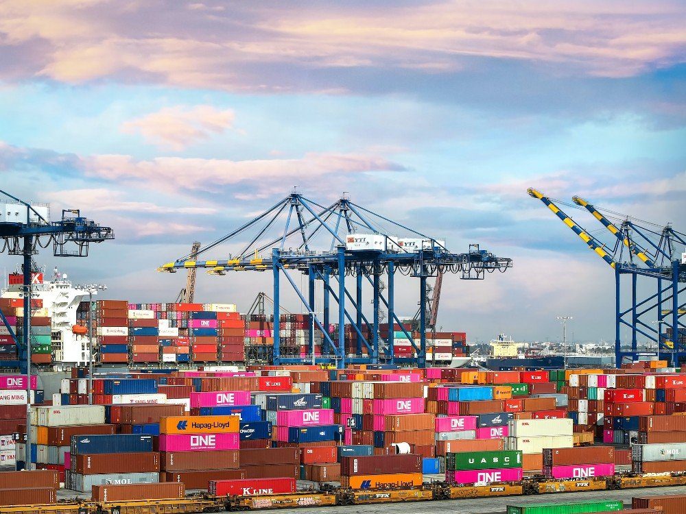 Several blue cranes above hundreds of differently colored shipping containers at a port.
