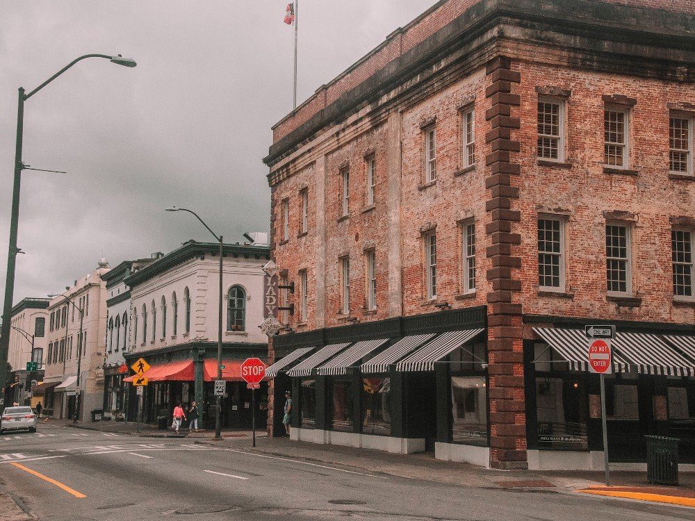 Cloudy day in downtown Savannah with an old red brick building in the foreground.