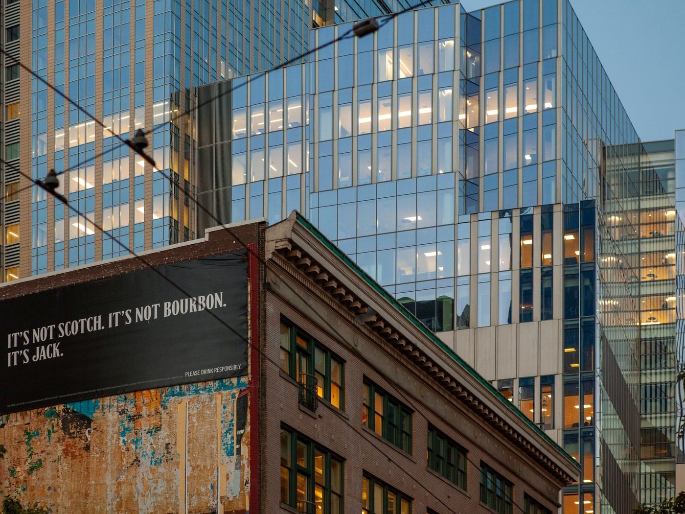 Office buildings with some lights on with an older office building in the foreground in Seattle.