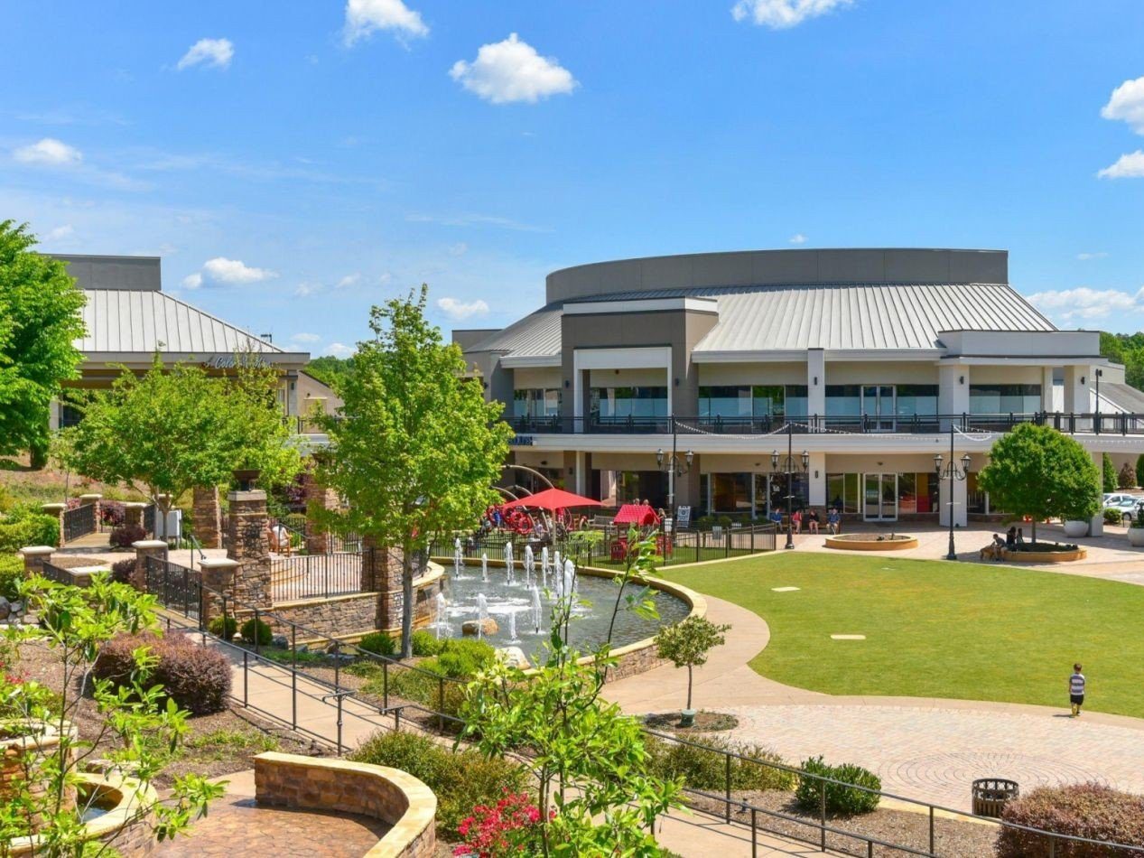 Two story retail property with a fountain and grassy areas with walking paths.