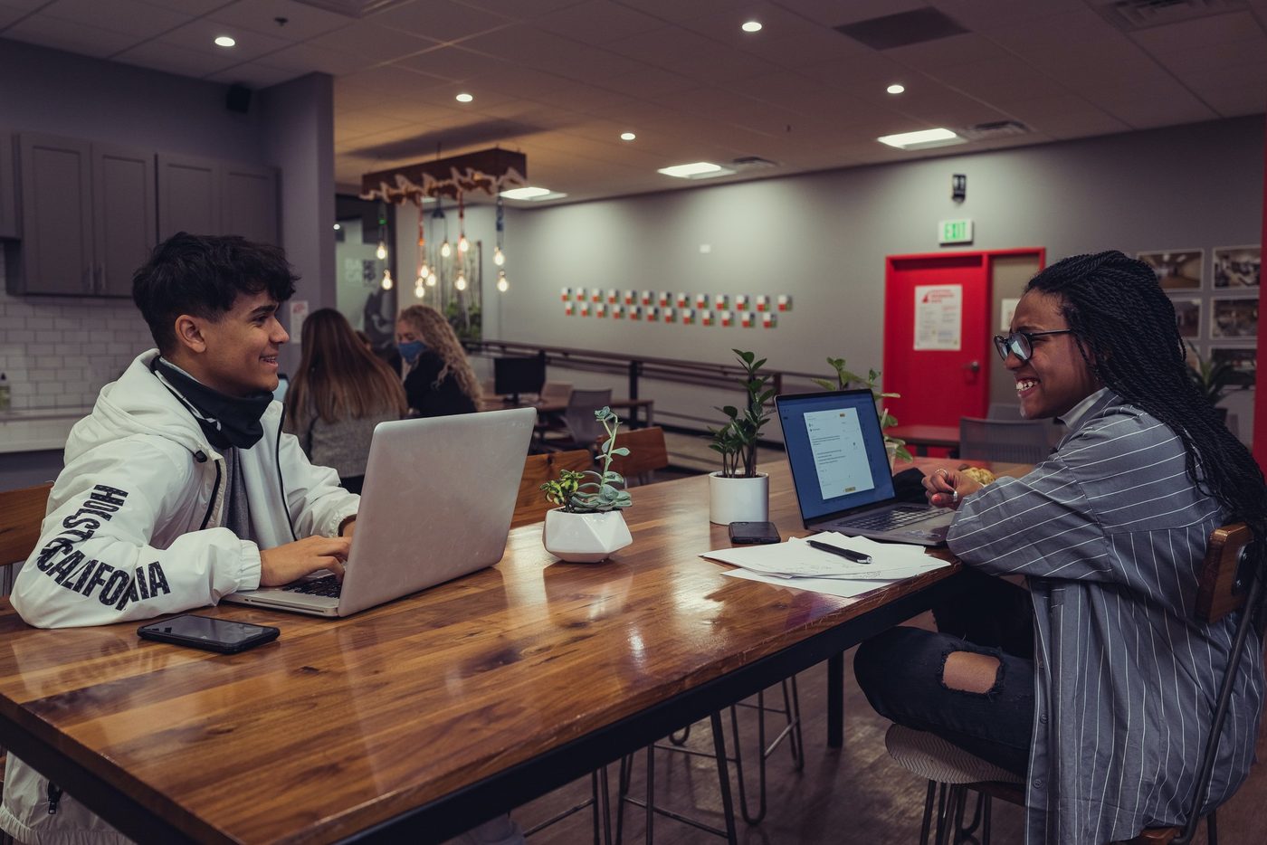 Two people sit at a table in a coworking space.