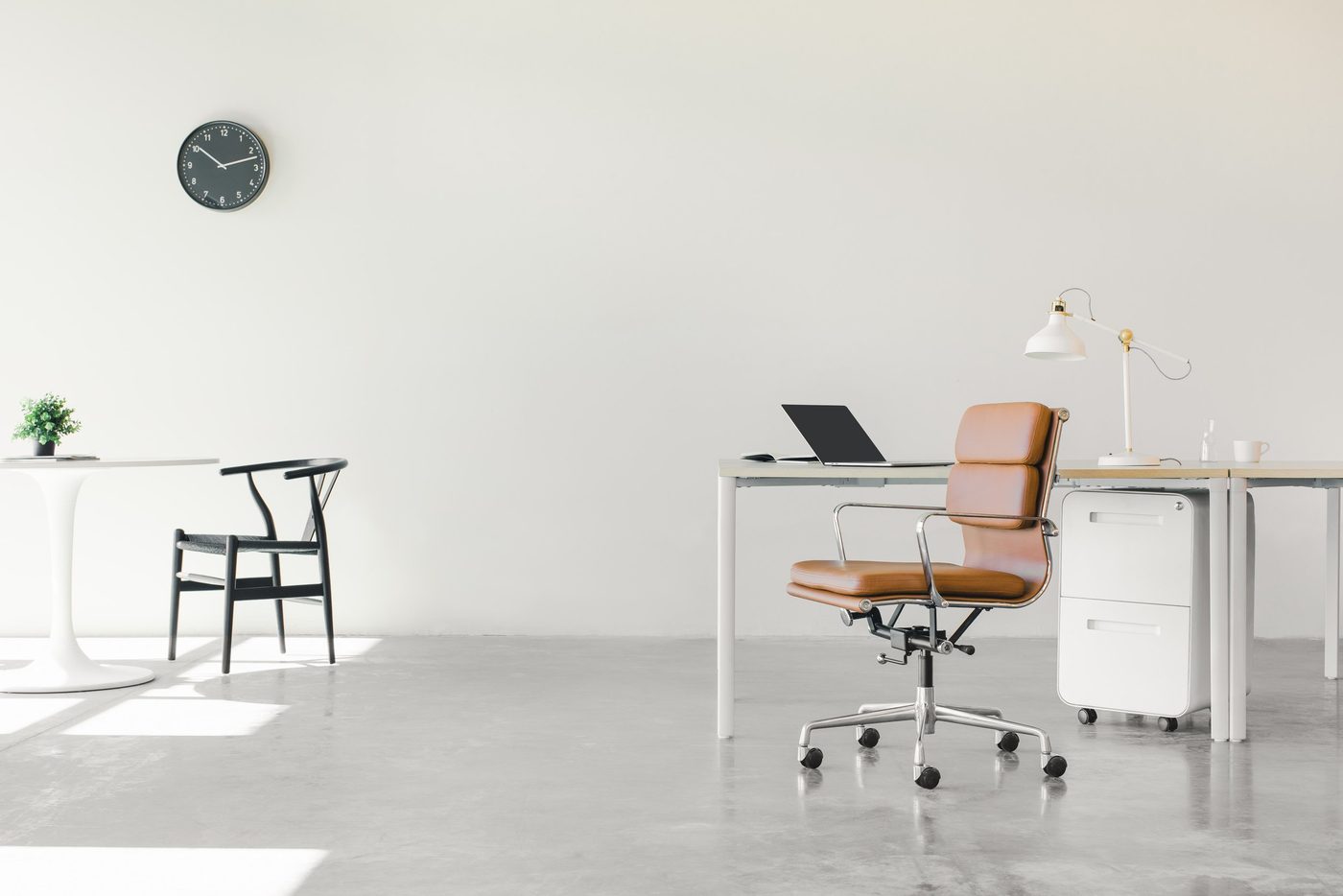 A white room with a table and a desk, both with unoccupied chairs.